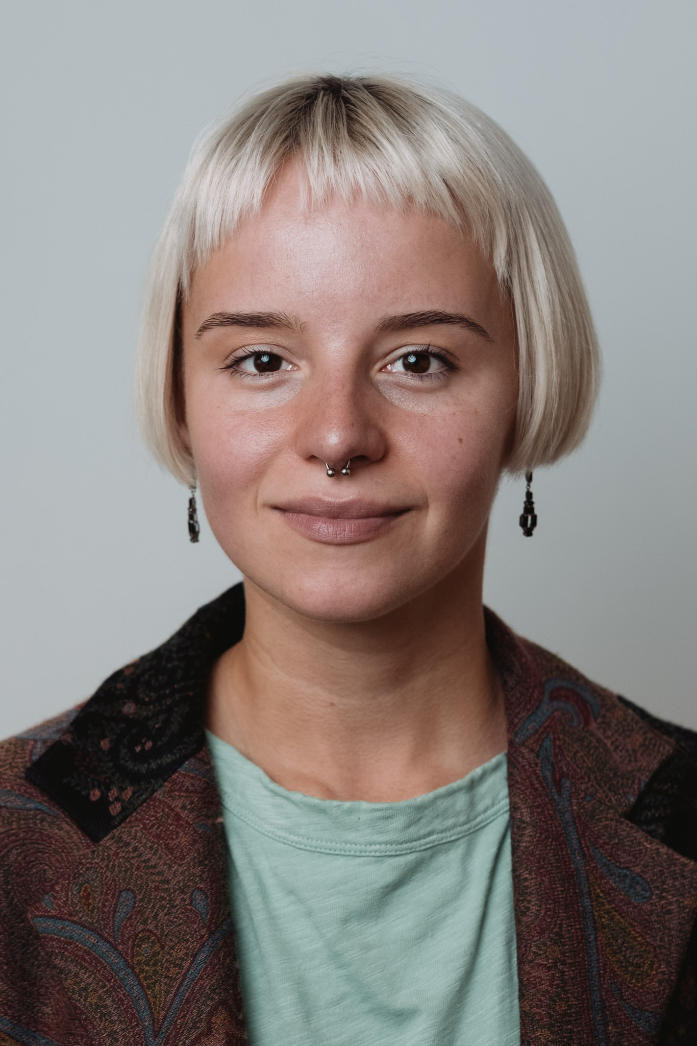 Corporate headshot — woman, soft studio light, neutral background.