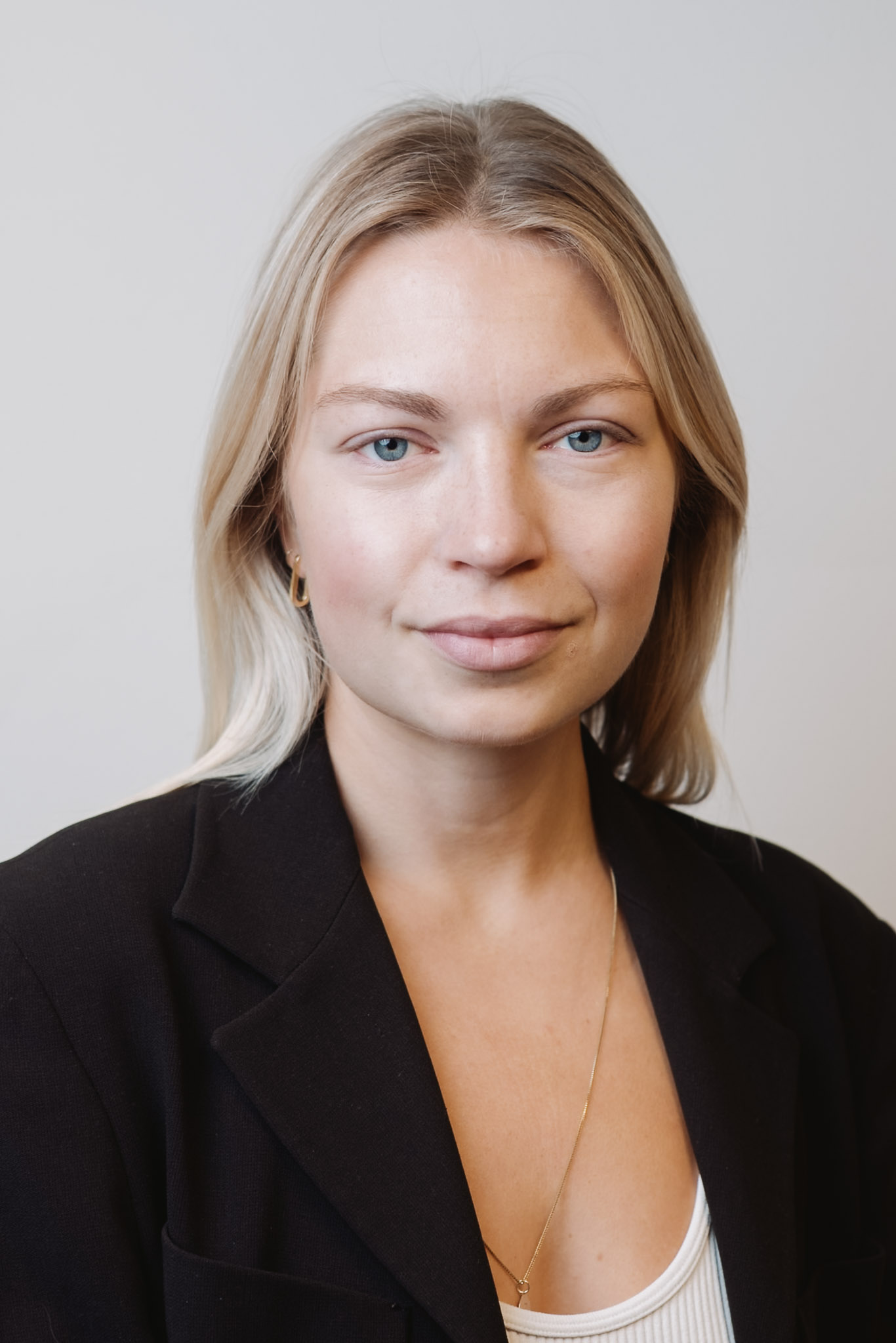 Studio headshot — woman in black blazer, clean studio light.