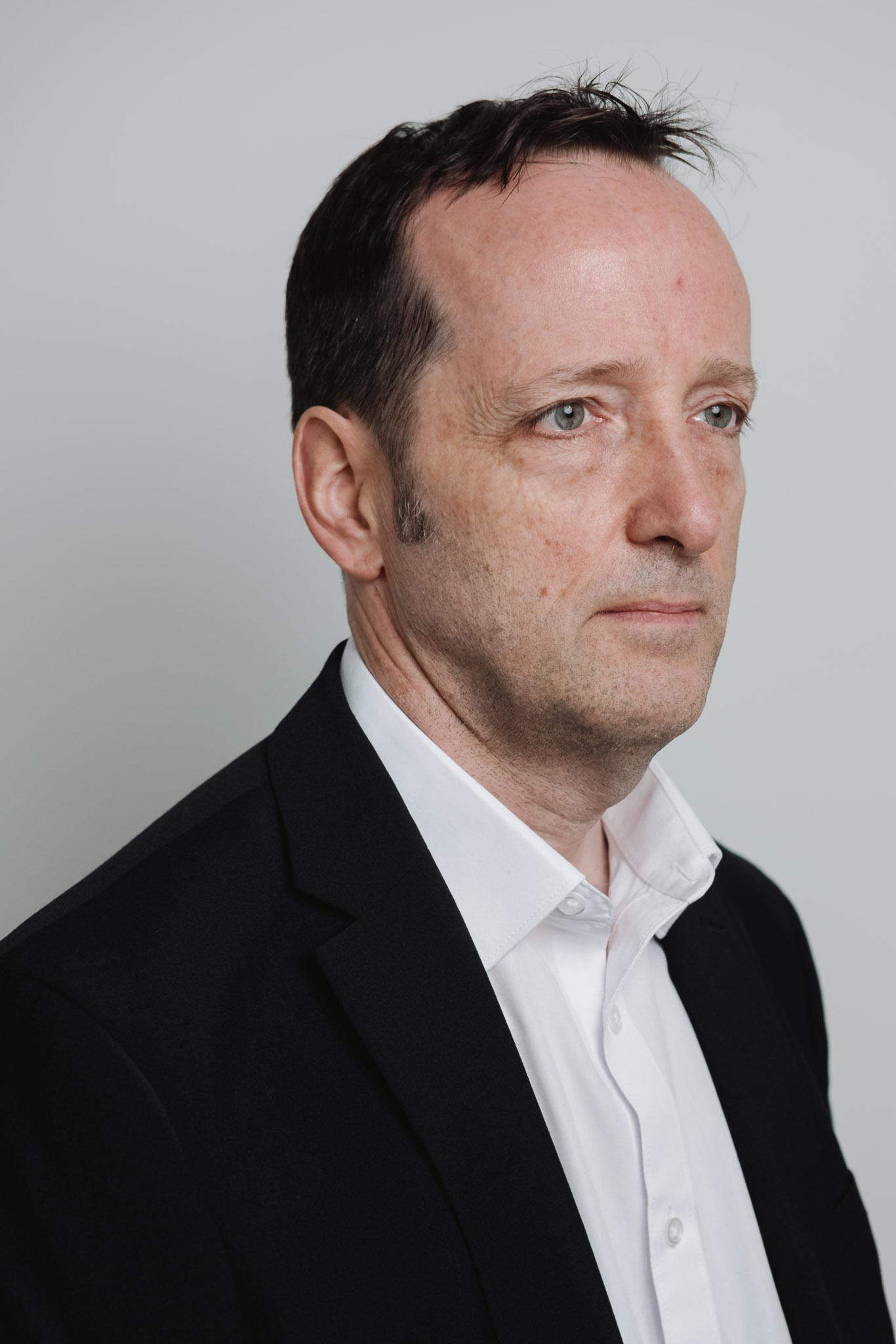 Corporate portrait — editorial angle, studio backdrop.